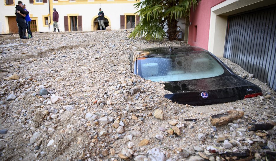 Des personnes se réconfortent devant une carcasse de voiture ensevelie sous les gravats. KEYSTONE